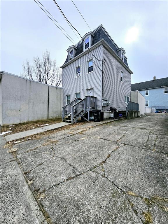 rear view of house featuring mansard roof