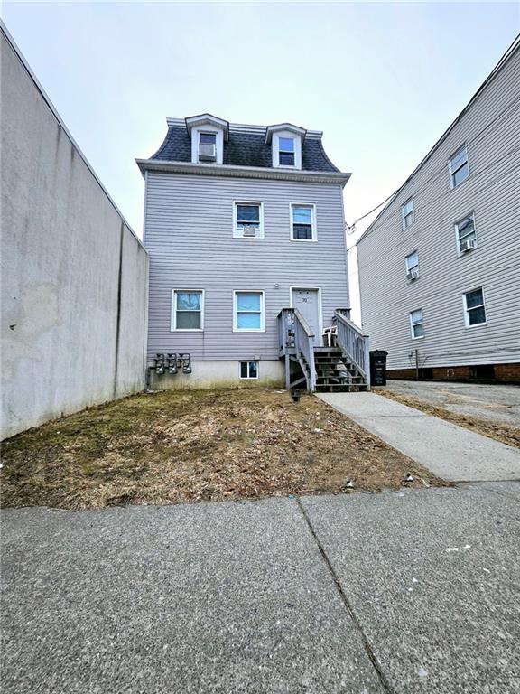 rear view of house with a shingled roof and mansard roof