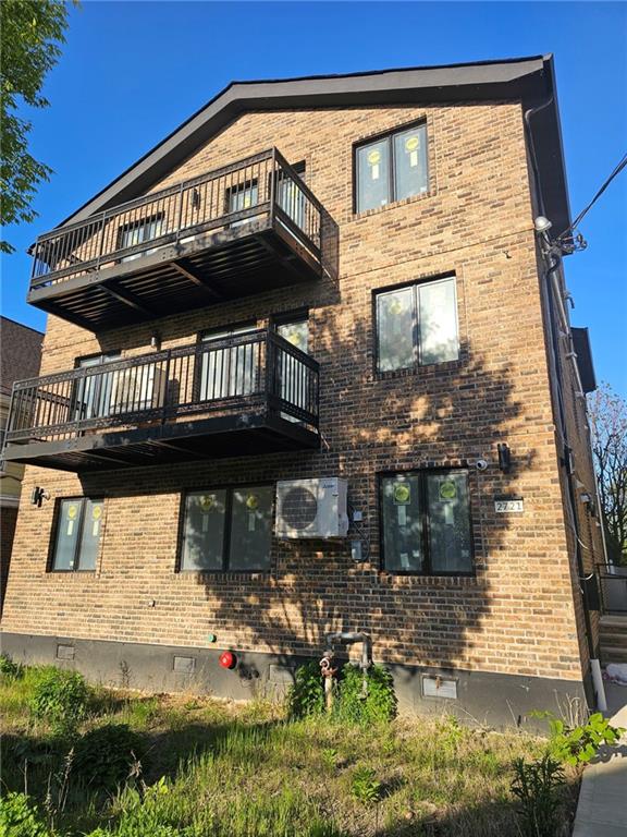 view of side of property with brick siding, ac unit, and a balcony