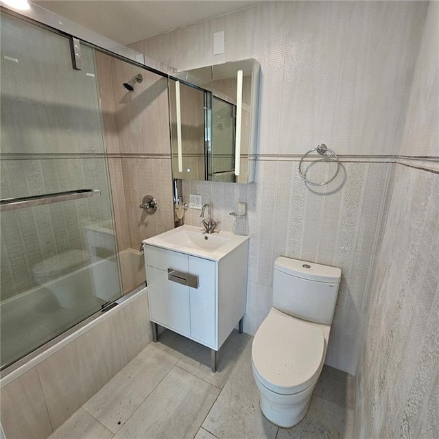 bathroom featuring toilet, tile patterned floors, shower / bath combination with glass door, and vanity