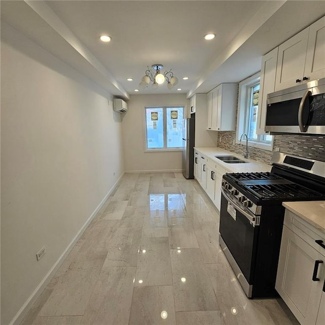 kitchen featuring an AC wall unit, stainless steel appliances, a wealth of natural light, and a sink