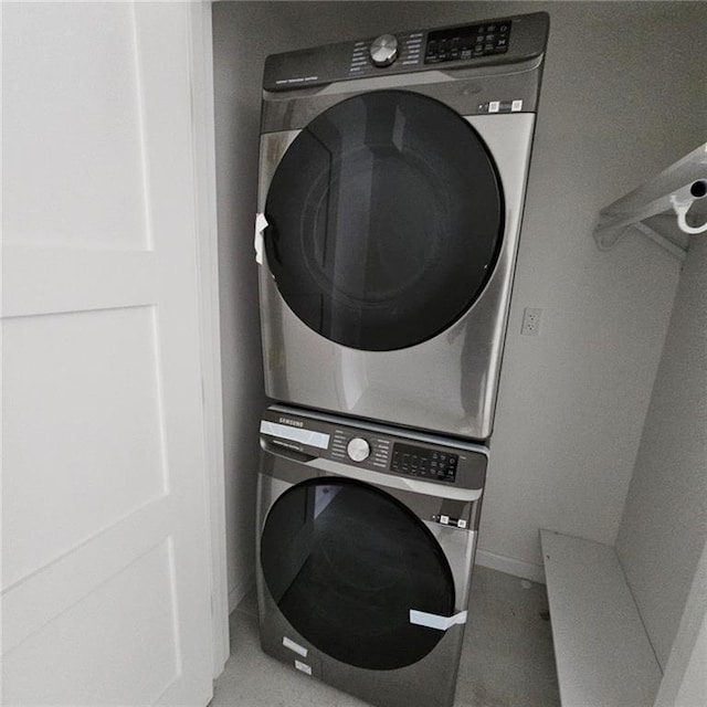 laundry room featuring baseboards and stacked washer / dryer
