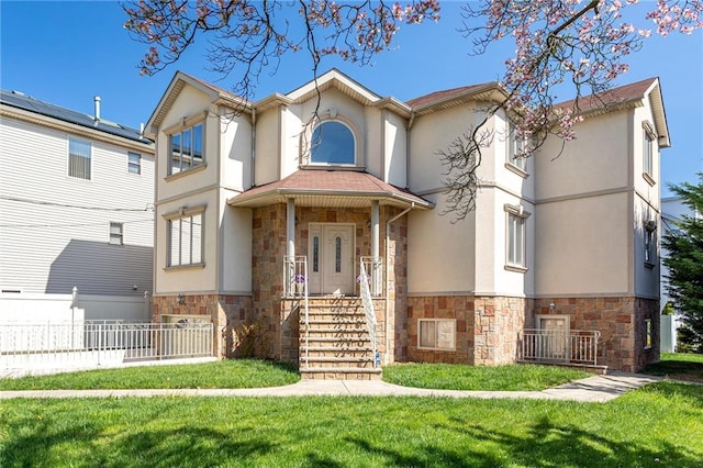 mediterranean / spanish-style home featuring a front lawn, stucco siding, stone siding, and fence