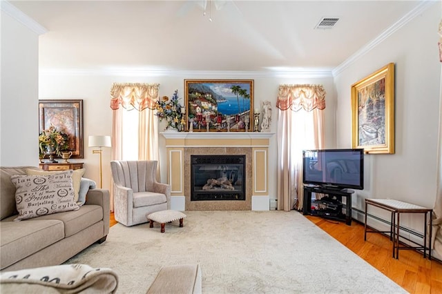 living area featuring crown molding, a tiled fireplace, visible vents, and wood finished floors