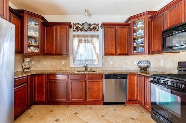 kitchen featuring light stone counters, a sink, and black appliances