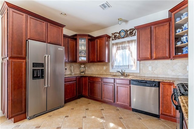 kitchen featuring visible vents, decorative backsplash, light stone countertops, a sink, and appliances with stainless steel finishes