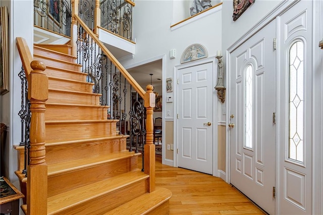 entryway featuring plenty of natural light, wood finished floors, stairway, and a towering ceiling