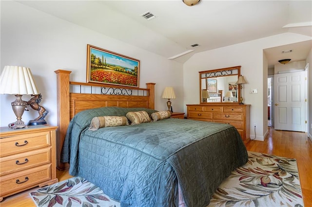 bedroom with baseboards, visible vents, lofted ceiling, and light wood-style floors