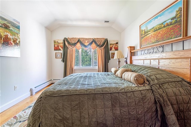 bedroom featuring visible vents, wood finished floors, baseboards, baseboard heating, and vaulted ceiling