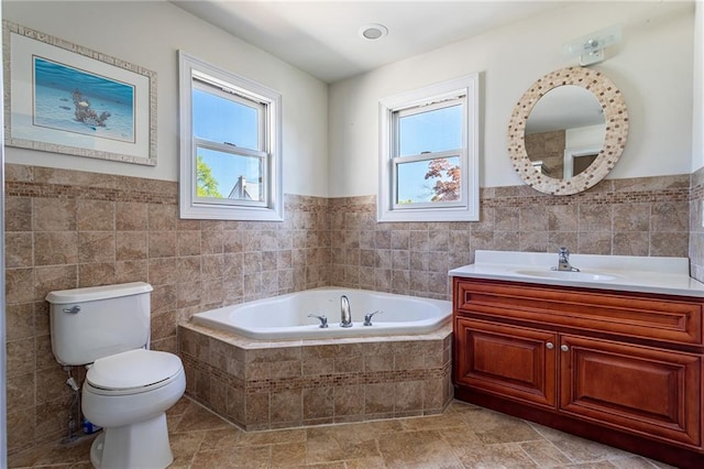 bathroom featuring toilet, tile walls, a healthy amount of sunlight, and a garden tub