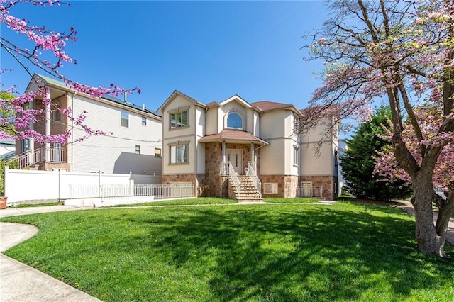 view of front of house with a front lawn, stucco siding, stone siding, and fence