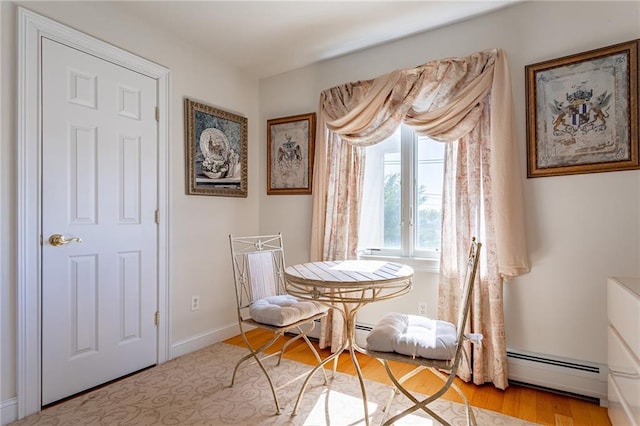 dining room featuring baseboards, a baseboard radiator, and light wood-style flooring