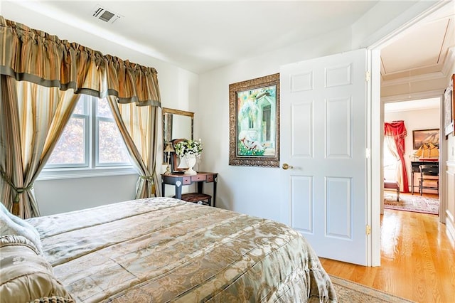 bedroom with light wood-type flooring, attic access, and visible vents