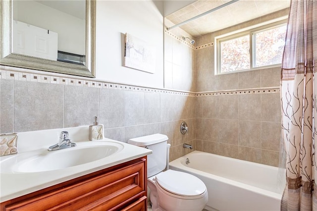 bathroom featuring tile walls, shower / bath combo with shower curtain, vanity, and toilet