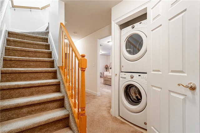 laundry room featuring stacked washing maching and dryer, baseboards, laundry area, and light colored carpet
