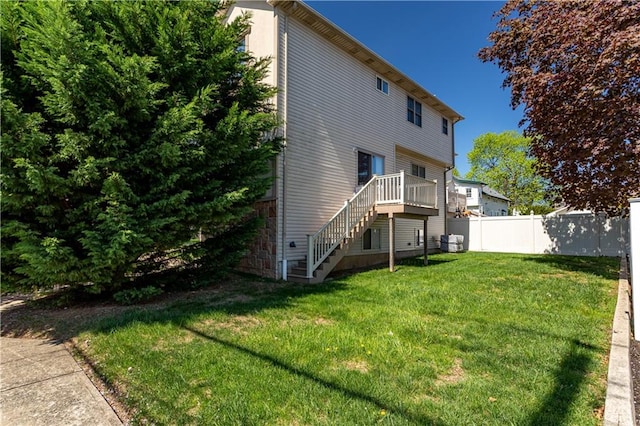 back of house featuring fence, stairs, a lawn, and a deck