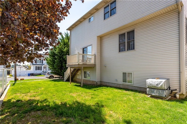 rear view of house featuring stairway, a deck, and a yard