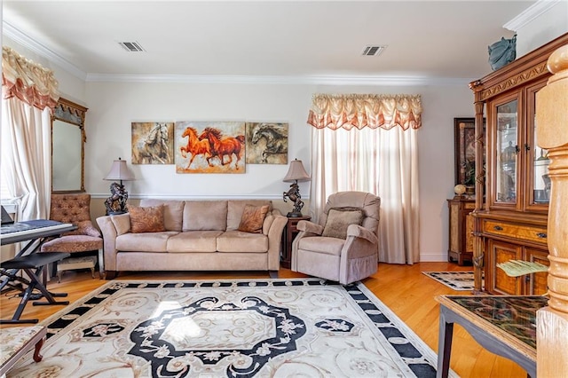 living area with visible vents, ornamental molding, a healthy amount of sunlight, and light wood-style floors