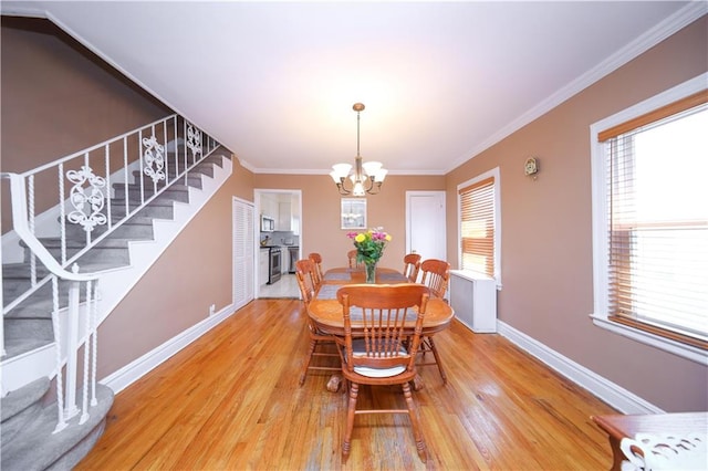 dining space featuring light wood-style floors, stairs, a healthy amount of sunlight, and an inviting chandelier