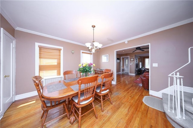 dining space with baseboards, ornamental molding, light wood-style flooring, and ceiling fan with notable chandelier