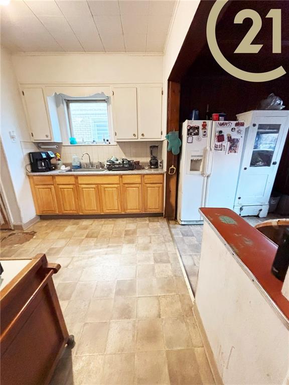 1817 E 15th St, Brooklyn, NY 11229 - kitchen with crown molding, backsplash, a sink, white cabinetry, and white refrigerator with ice dispenser