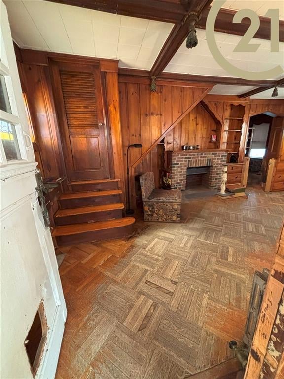 1817 E 15th St, Brooklyn, NY 11229 - unfurnished room with wooden walls, stairway, a fireplace, and beam ceiling