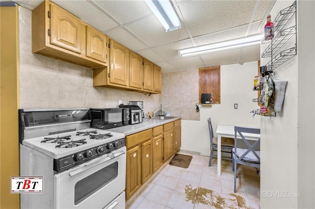 1854 73rd St, Brooklyn, NY 11204 - kitchen with white gas stove, black microwave, light countertops, a drop ceiling, and a sink