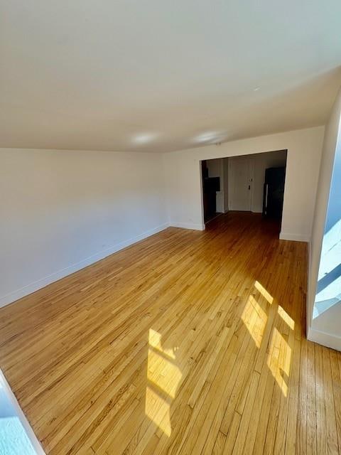 spare room with baseboards and light wood-style floors