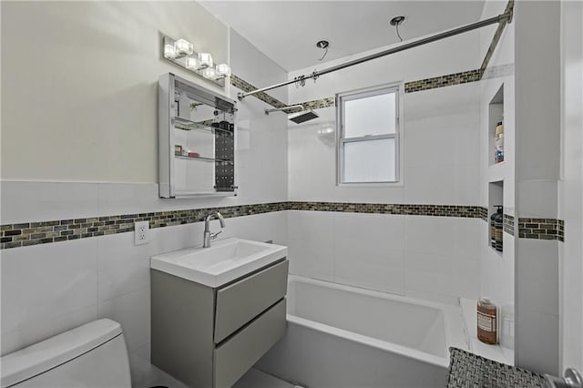 full bathroom with toilet, tile walls, washtub / shower combination, and vanity