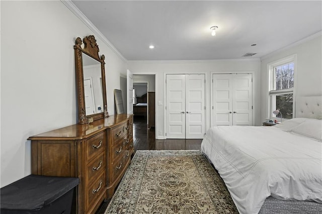 bedroom featuring visible vents, crown molding, dark wood-style flooring, two closets, and recessed lighting