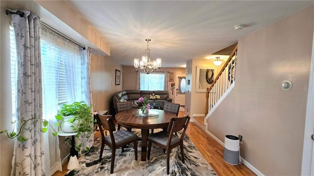 dining room with an inviting chandelier, baseboards, stairway, and light wood-type flooring