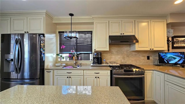 kitchen with light stone counters, a sink, stainless steel range with gas stovetop, under cabinet range hood, and refrigerator with ice dispenser