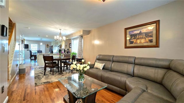 living area featuring an inviting chandelier, baseboards, and light wood-type flooring