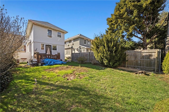 rear view of house with a yard, a wooden deck, and a fenced backyard