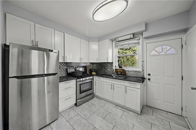 kitchen with decorative backsplash, dark countertops, marble finish floor, stainless steel appliances, and white cabinetry