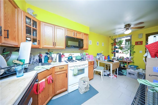 kitchen with ceiling fan, white gas range oven, black microwave, light countertops, and glass insert cabinets