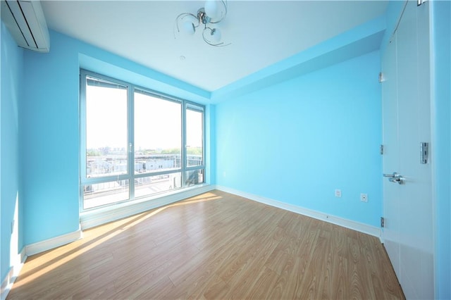 empty room featuring baseboards, a wall mounted air conditioner, and wood finished floors