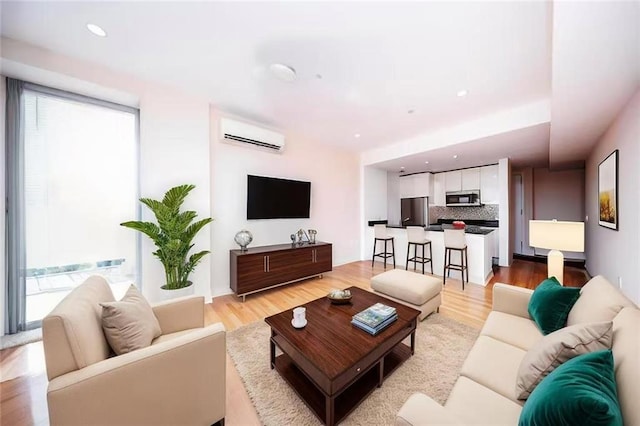 living room featuring plenty of natural light, light wood finished floors, and a wall unit AC