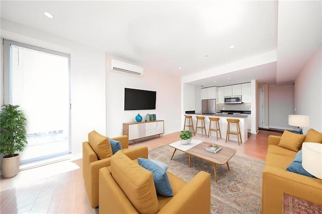 living area with an AC wall unit, recessed lighting, and light wood-style floors