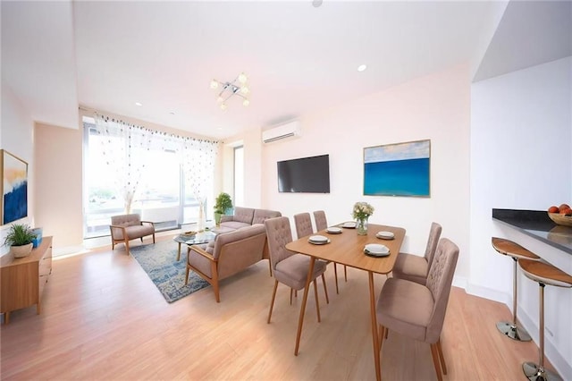living room with baseboards, a wall mounted AC, and light wood-style flooring