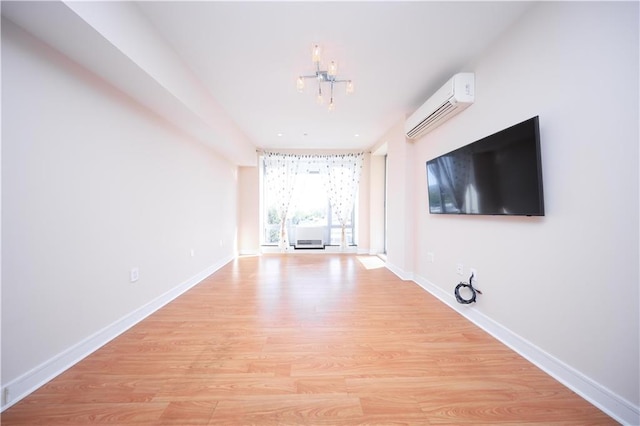 unfurnished living room featuring light wood-style floors, baseboards, and a wall mounted AC