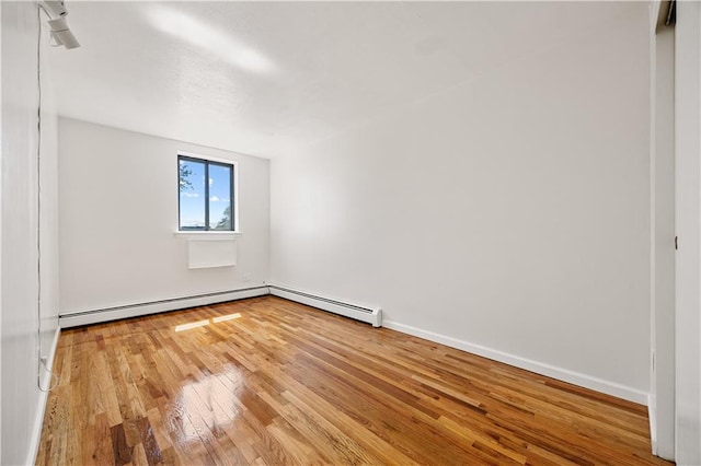 spare room with baseboards, baseboard heating, and hardwood / wood-style floors