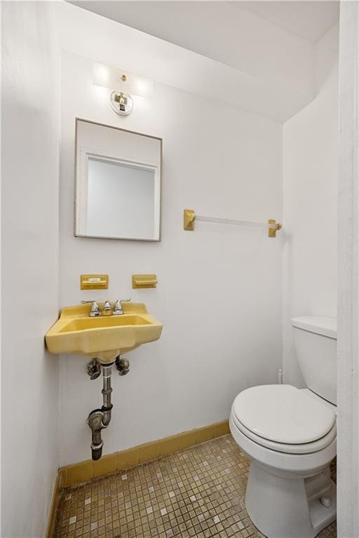 bathroom featuring toilet, baseboards, tile patterned flooring, and a sink