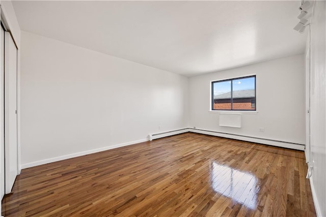 unfurnished bedroom with wood-type flooring, baseboards, baseboard heating, and a closet
