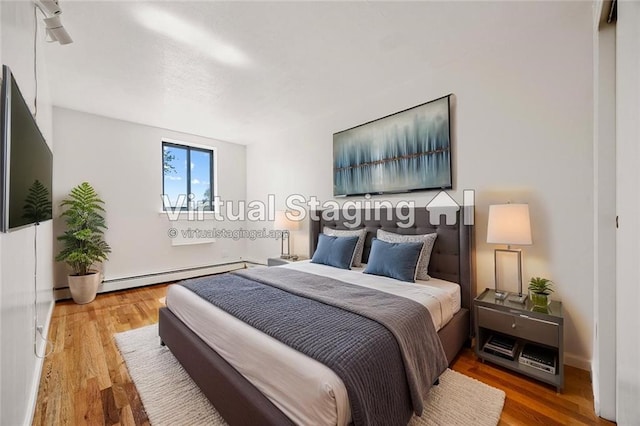 bedroom with a baseboard heating unit and wood finished floors