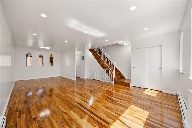 unfurnished living room with stairs, wood finished floors, baseboard heating, recessed lighting, and a baseboard heating unit