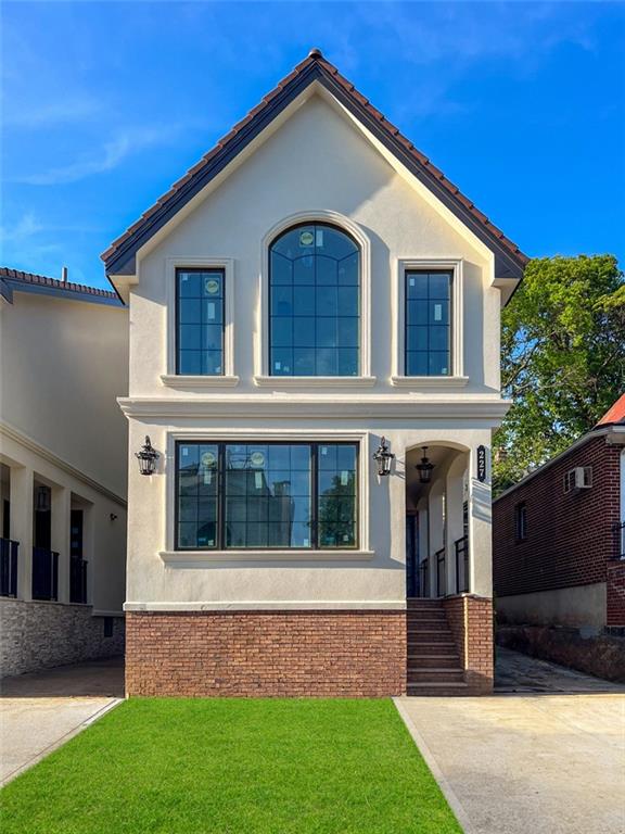 227 77th St, Brooklyn, NY 11209 - view of front of home featuring a front yard, stucco siding, and a porch