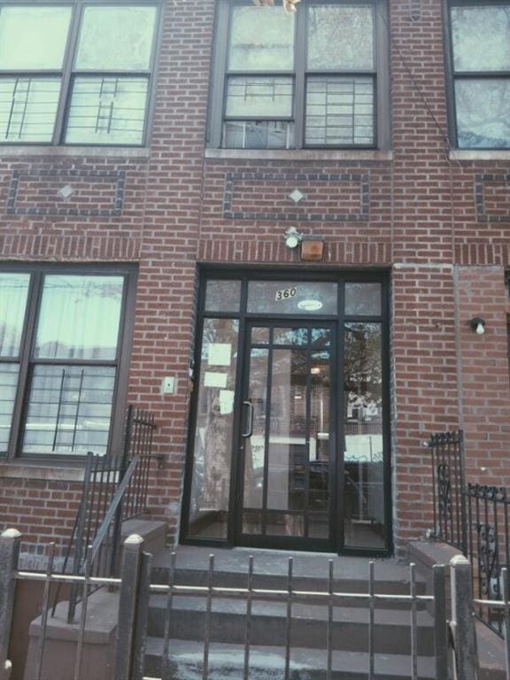 property entrance featuring fence and brick siding