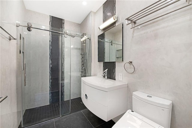 bathroom with vanity, tile walls, a stall shower, and toilet