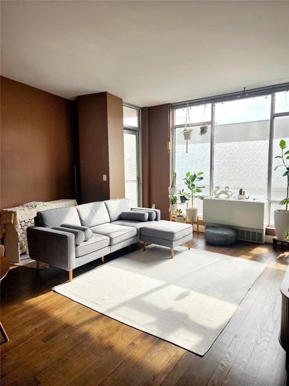 living room featuring a wall of windows, radiator heating unit, and hardwood / wood-style flooring